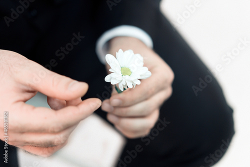 Romantic. Man's hands. A man sits in a jacket with a flower in his hands and picks the petals from it. Divination