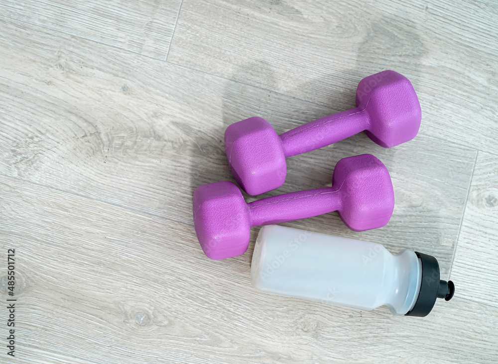 green round ball colored dumbbells barbell water female top spread out on a mat. green round ball colored dumbbells barbell water female top spread out on a mat.