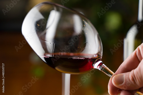 Wine tasting. A glass of red wine on the background of a restaurant table with bottle at an evening dinner or event party. photo