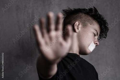 Fototapeta Naklejka Na Ścianę i Meble -  Sad teen boy covered his mouth. Problems of suppression of emotional detachment and isolation of adolescent children. Difficulties growing up during the transition period
