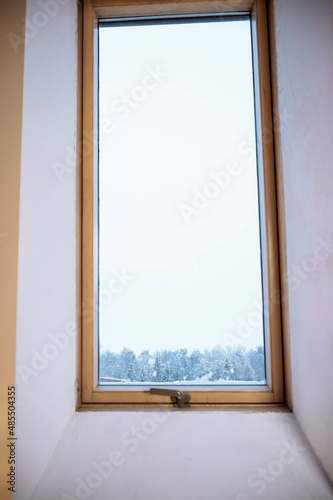 wooden window in the wall in the attic room. Winter outside the window