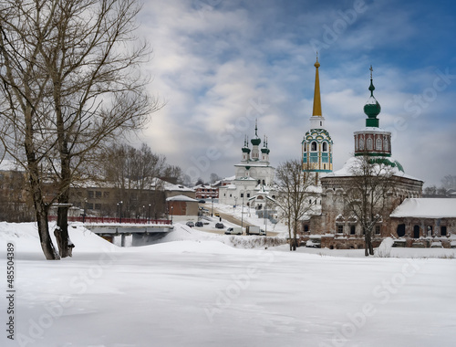 View of the historical part of the provincial town of Solikamsk (Northern Urals, Russia) with its ancient churches, bell towers against a blue sky with clouds and snowdrifts. Ancient city architecture