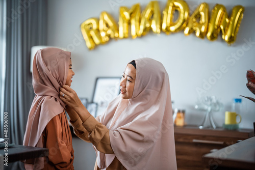 muslim mother fixing her dauhgter headscarf on ramadan photo