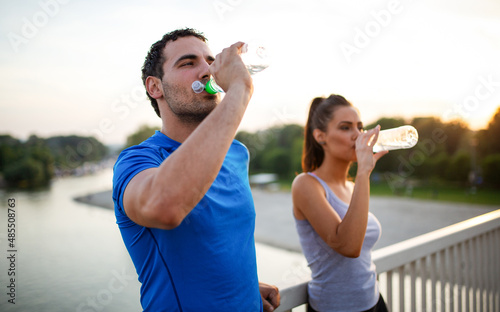 Portrait of happy fit sporty couple relaxing after a running outdoors.