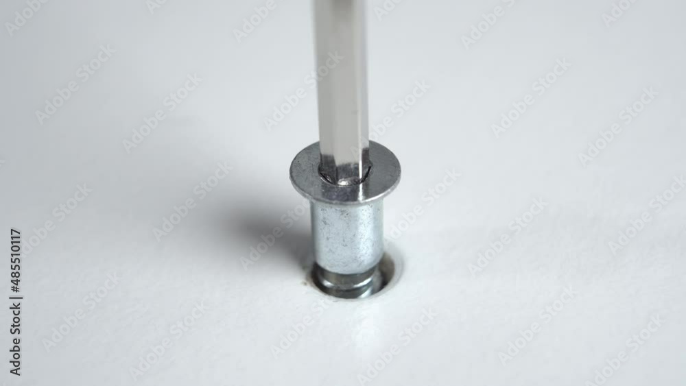 Fixing the furniture screw with a hex wrench. Using an allen key to assemble a white nightstand. Macro Fixing the furniture screw with a hex wrench. Using an allen key to assemble a white nightstand. Macro