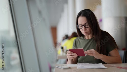 adult woman is checking form for visa and passport before traveling, sitting in cafe of terminal