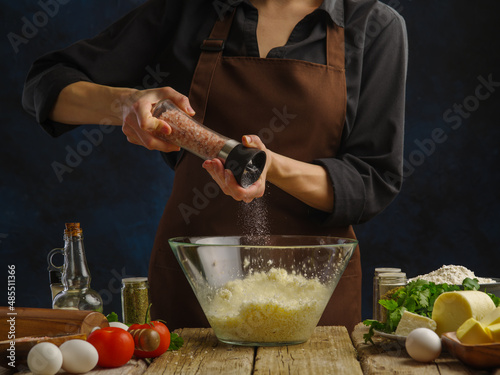 The chef adds spices to grated cheese. Ingredients - vegetables, eggs, herbs, spices on a wooden table. cooking pizza, salad, sauce, pasta. Advertising. banner, restaurant, cafe. photo