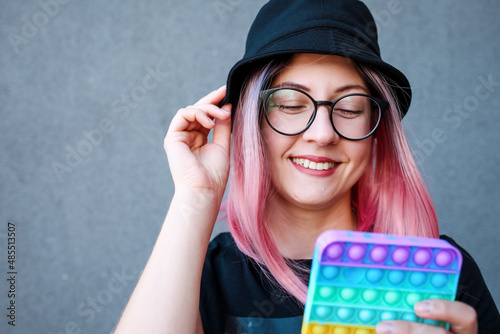 Young Girl Holding pink Pop It Fidget Toy in hands. Teen Playing