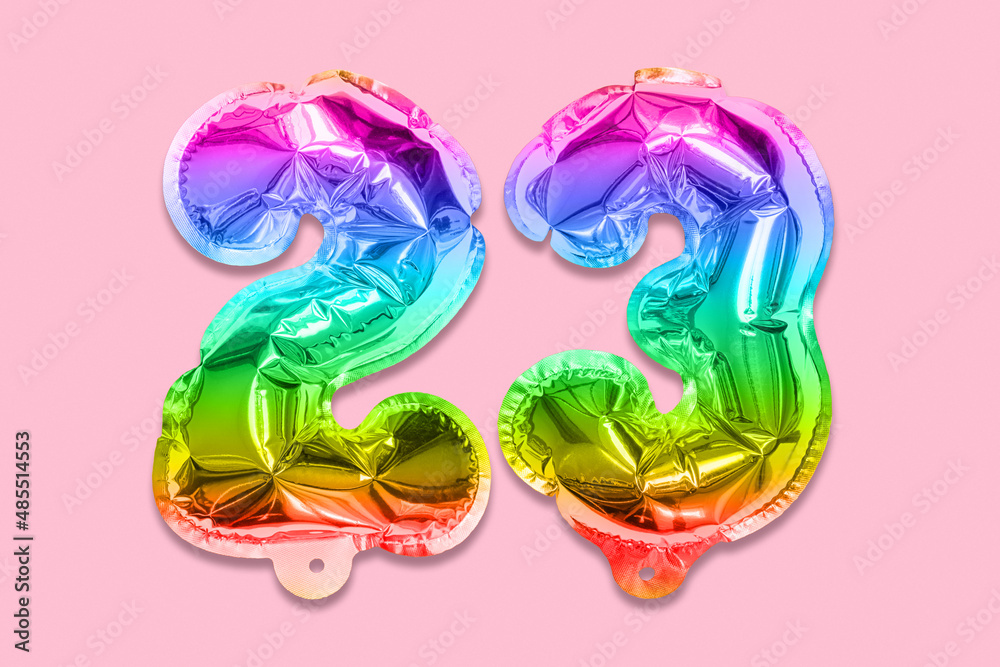 Rainbow foil balloon number, digit twenty three on a pink background. Birthday greeting card with inscription 23. Top view. Numerical digit. Celebration event, template. Rainbow foil balloon number, digit twenty three on a pink background. Birthday greeting card with inscription 23. Top view. Numerical digit. Celebration event, template.