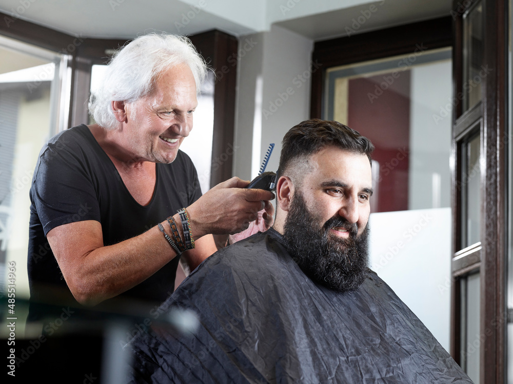 Smiling hairdresser cutting man's hair in hair salon Smiling hairdresser cutting man's hair in hair salon