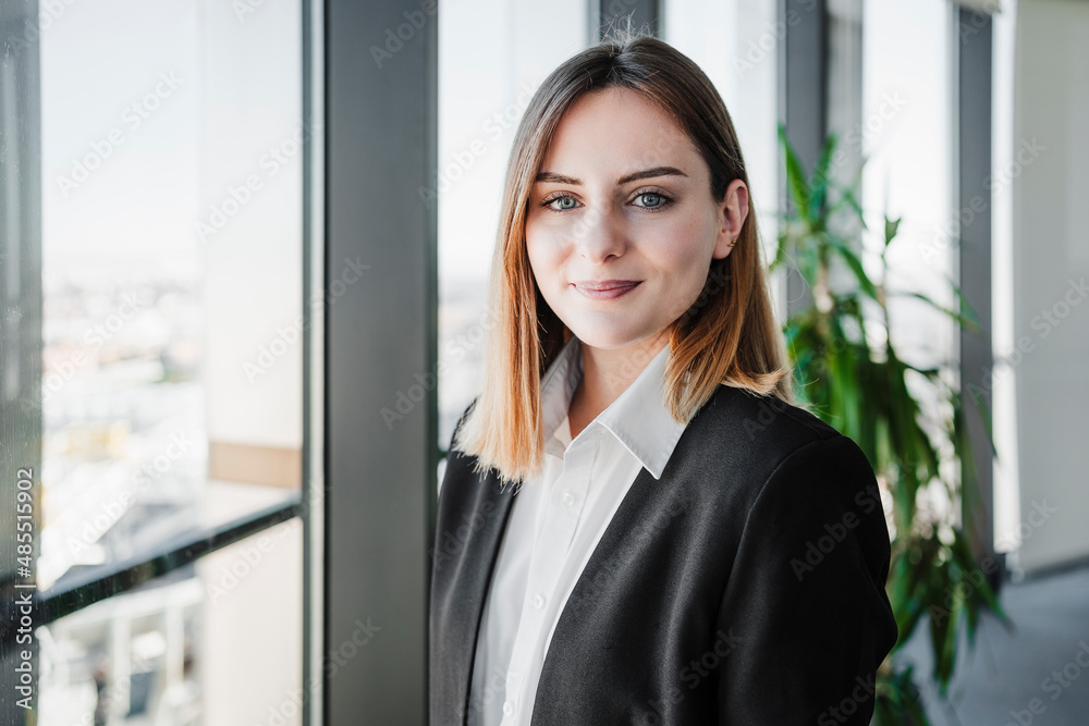 Beautiful working woman smiling near window in office Beautiful working woman smiling near window in office