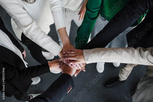 Businesswomen and businessmen stacking hands in office photo