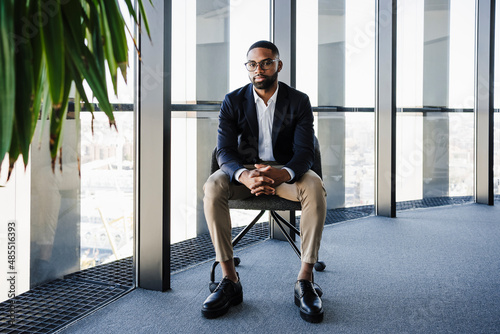 Businessman with hands clasped sitting on chair in office