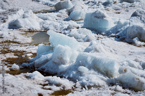 Ice drift on the Amur River. Melting ice floes in spring. A heap of blocks and fragments. Sunny day. Glare and shadows.