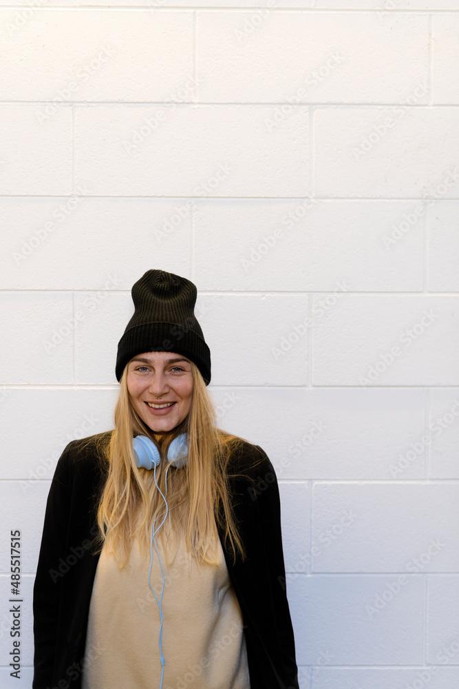 Happy woman with headphones in front of wall Happy woman with headphones in front of wall