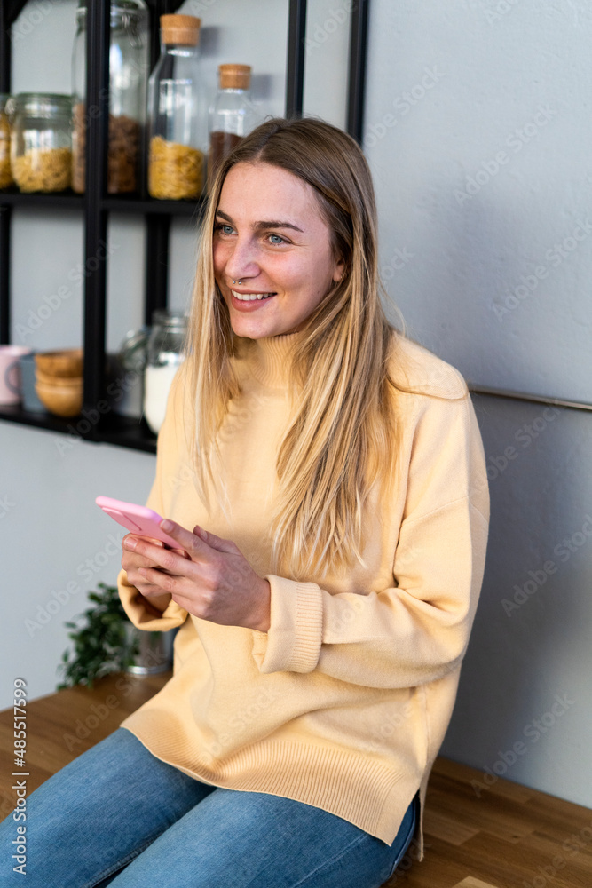 Thoughtful woman with smart phone in kitchen Thoughtful woman with smart phone in kitchen