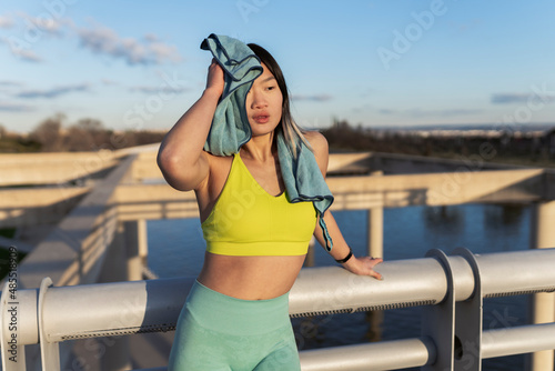 Tired woman wiping sweat in front of railing