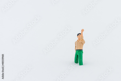 Miniature toy man holding something, white snow background.copy space.Outdoors shot.