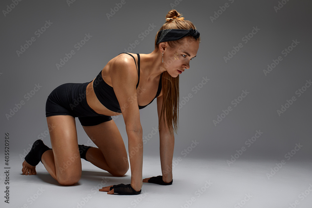 Obraz premium Portrait of female anger, animal instinct, demonstrating their incredible flexibility with the movement of animal flow in the studio on a gray background.