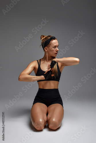 Fototapeta Naklejka Na Ścianę i Meble -  Animal instinct fitness female instructor showing his incredible flexibility with an animal flow move in studio against a gray background