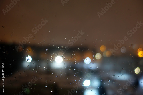 View from window with rain drops on night city.