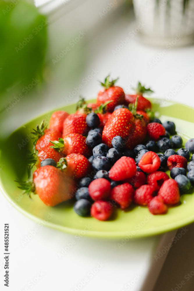 Plate of blueberries, raspberries and strawberries on table