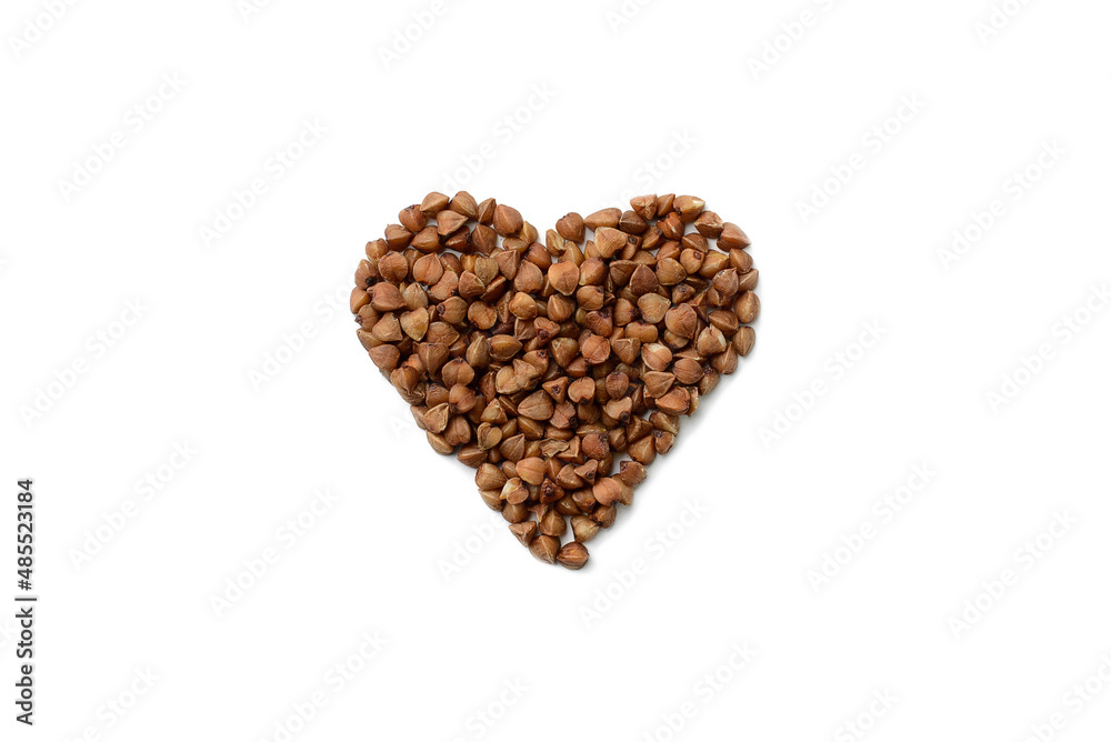 Buckwheat grains stacked in the shape of a heart on a white isolated background, top view.