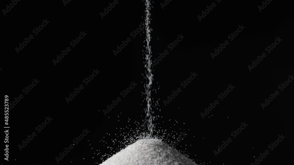 Particles of white dry sand are pouring down forming hill on an isolated black background. Close up shot of crumbling natural sand grains, sandy dune. Heap of petrified natural mineral.