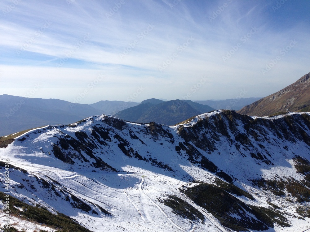 Snowy mountain peaks and a blue sky at the background. Snowy mountain surface. Scenic view on Rosa Peak, Sochi. Mountain ridge. Snowy landscape, wintertime. Cold. Peak