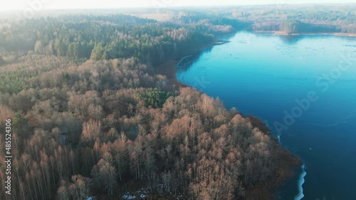 Drone aerial flight over the frozen lake in the winter forest through the fog