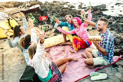 Alternative friends having fun together at beach camping party - Life style travel concept with happy people travelers toasting and drinking bottled beer at summer surf camp - Bright multicolor filter