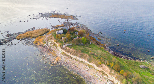 Aerial view to the thin cape badly suffering by coastal erosion and with the abandoned historic coast guard station buildings, nearly collapse to sea