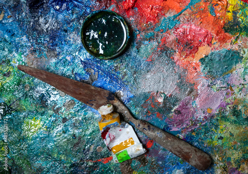 Artistic palette knife and tube of paint  on a wooden palette