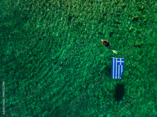 summer greece vacation woman floating in water with flag