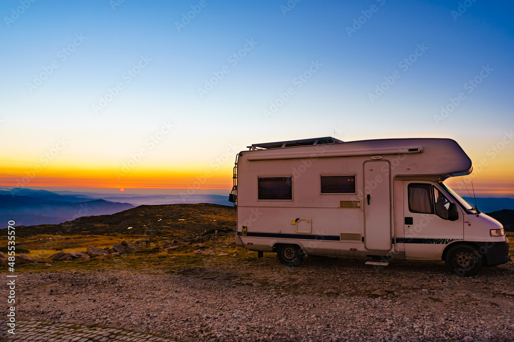 Rv camper in mountains above clouds at sunset