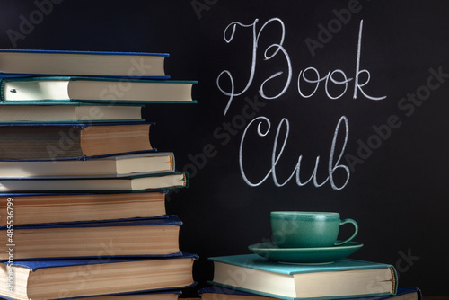 Book Club Concept. A stack of hardcover books with a cup of coffee and chalk lettering on a blackboard