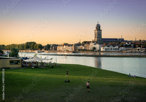People play football at a beach bar on the other side of the river from the city of Deventer with the skyline as a view