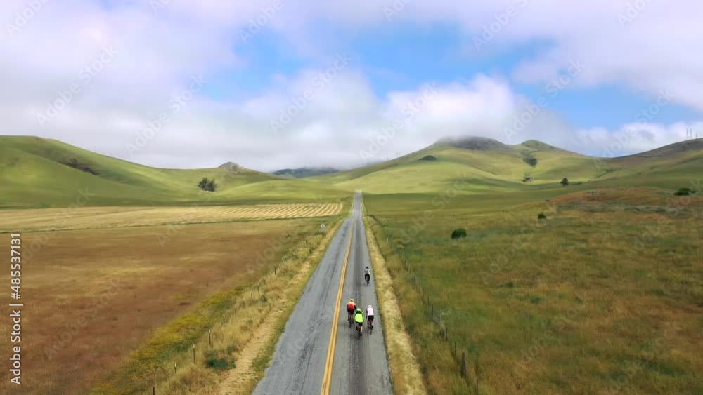 Scenic Landscape with Cyclists Riding on Road through Mountains - aerial drone shot Scenic Landscape with Cyclists Riding on Road through Mountains - aerial drone shot