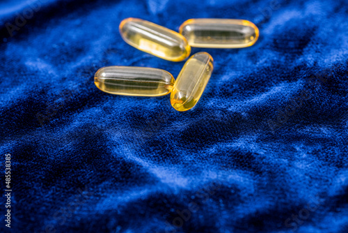 Fish oil capsules on a dark blue plush cloth