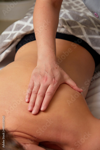 Massagist performing back massage to female client.