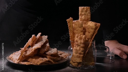 Sfrappole or chiachiere or angel wings. Carnival food TYPICAL. Traditional sweet crisp pastry deep-fried and sprinkled with powdered sugar.crispy dessert festive in female hands. 4k photo