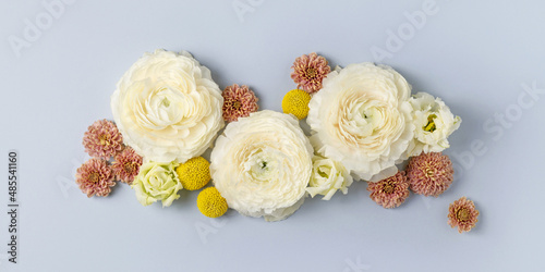 Pastel fresh white, pink and yellow flowers on light blue background. Tender floral composition. Blossom spring banner. Holiday postcard. Ranunculus, chrysanthemum, lisianthus. Top view, flat lay.