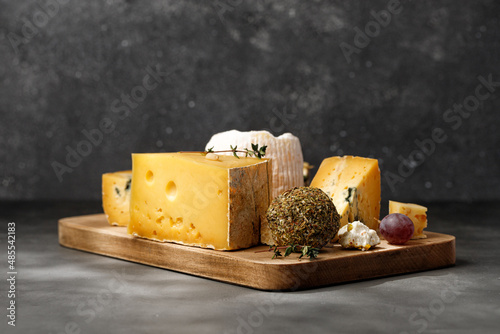 Assortment of different cheese types on wooden board on dark background. photo