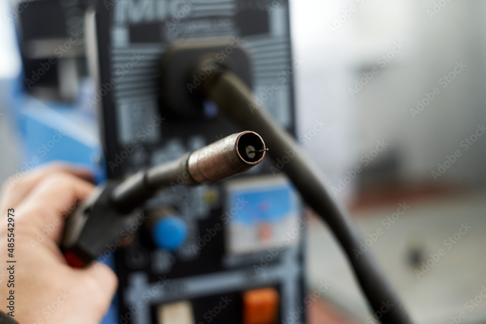 Fototapeta premium A human hand holds a burner that feeds wire for welding parts.