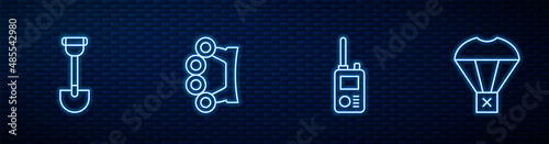 Set line Walkie talkie, Sapper shovel, Brass knuckles and Box flying on parachute. Glowing neon icon on brick wall. Vector
