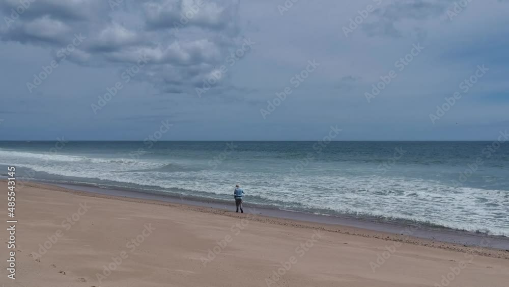 Lonely Single Fisherman Standing on Cape Cod Beach Fixing His Fishing Rod Reel Lonely Single Fisherman Standing on Cape Cod Beach Fixing His Fishing Rod Reel