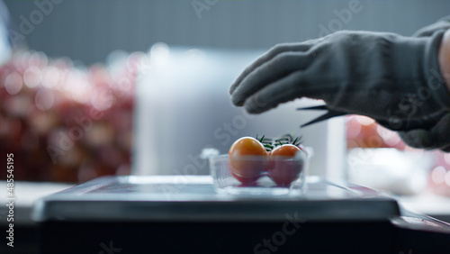 Worker hands packing cherry tomatoes plastic box removing parts cutting closeup photo