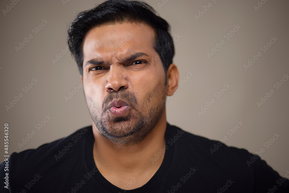 Close-up portrait of a disappointed angry young man against dark background Close-up portrait of a disappointed angry young man against dark background