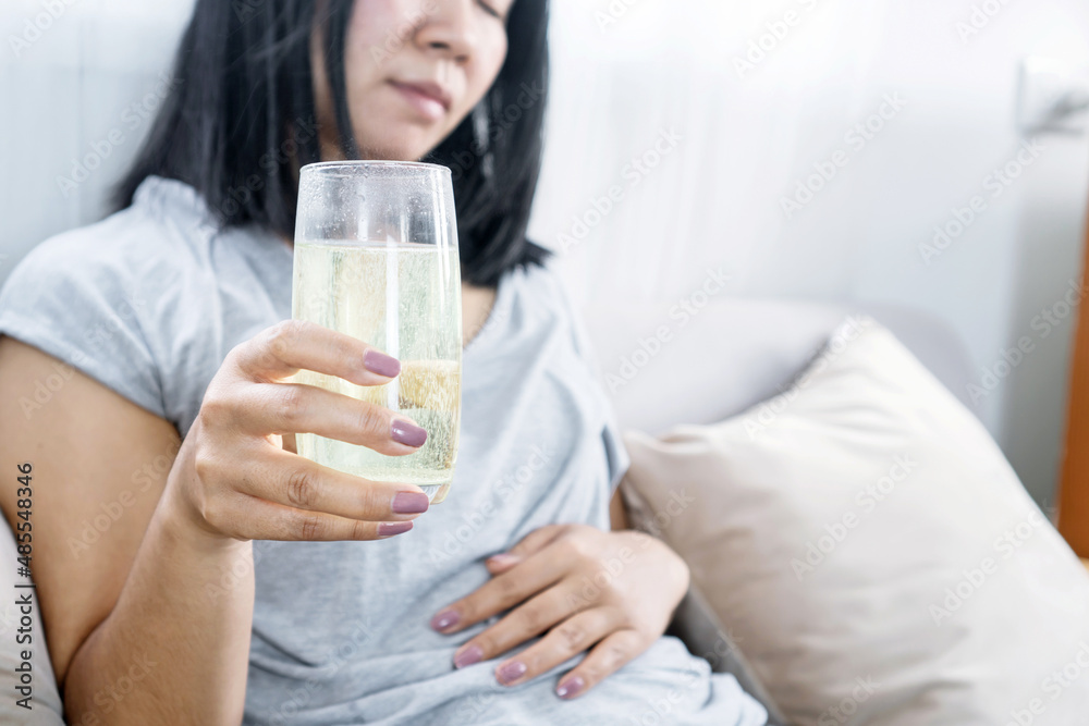 woman having flatulence drinking a glass of fruit salt for relief indigestion, acidity problem hand holding her stomachache woman having flatulence drinking a glass of fruit salt for relief indigestion, acidity problem hand holding her stomachache