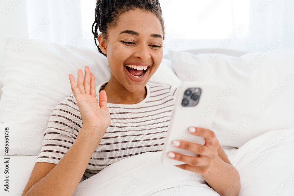 Young black woman reading book while lying on bed Young black woman reading book while lying on bed